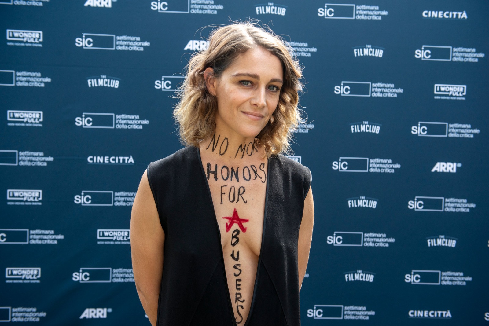 Ariane Labed nel photocall di The Vordulak, selezionato alla Settimana della Critica, mostra sul proprio corpo il dissenso per la presenza al Lido di registi coinvolti in storie di abusi