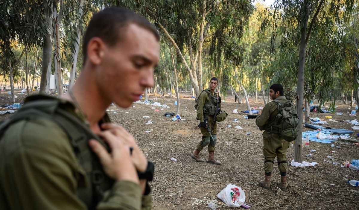 Membri delle forze di sicurezza israeliane alla ricerca di effetti personali in grado identificare le vittime dei massacri presso il Kibbutz Re'im vicino al confine con Gaza (12 ottobre 2023) 